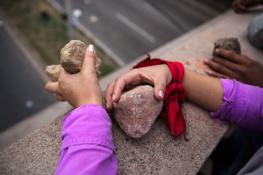 A supporter of opposition presidential candidate Salvador Nasralla on a bridge holds rocks to throw at police